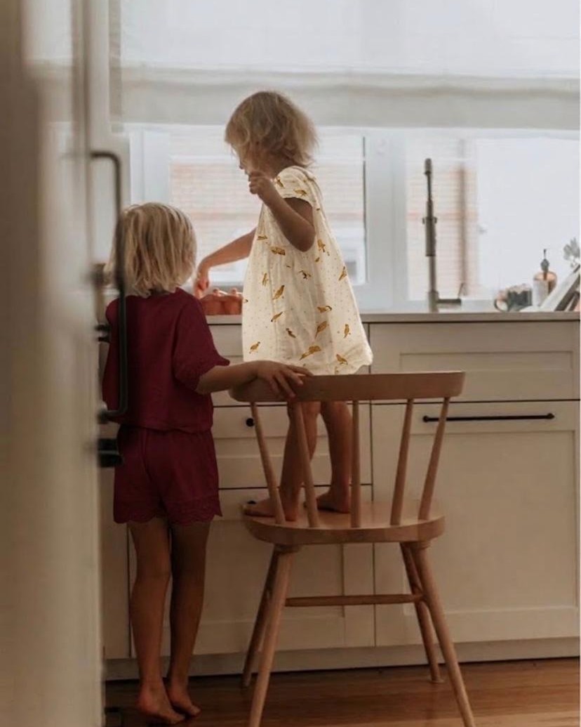 Two small children at a kitchen counter, one standing on a chair